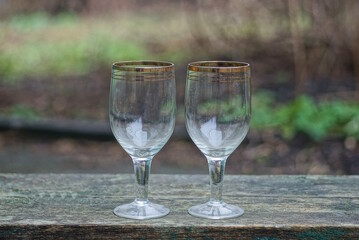 white two big glass crystal goblets on a gray wooden table outdoors 