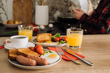 Grilled sausage with toast and fried egg, home cooked English breakfast with cup of black coffee and orange juice in the kitchen