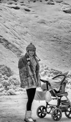 Naklejka premium Infrared view of a woman with her daughter in a stroller, walking in the snowy road