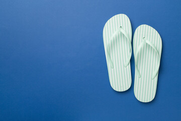 Striped flip flops on color background, top view