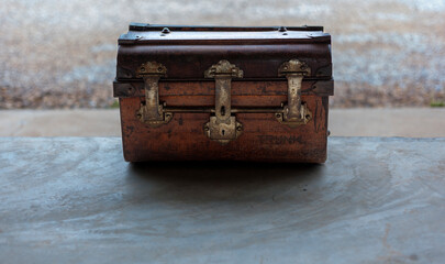 An ancient locked wooden chest laying on the cement floor.