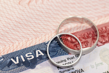 Wedding rings on passport with us visa as concept of marriage of convenience