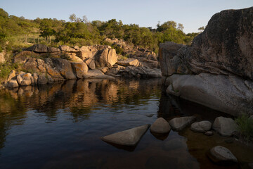 View of the serene river and rocky cliffs at sunset. 