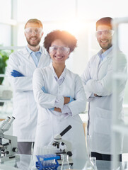 Smiling scientists looking at camera arms crossed in laboratory