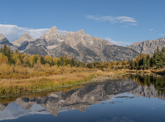 Grand Teton Mountain Range with autumn colors reflect in water of Snake River at Schwabacher’s Landing, Grand Teton National Park