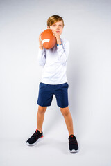 Cute young athlete posing with football raised near his face