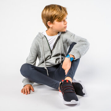 Blond little boy sitting casually on floor with legs crossed