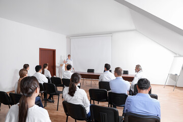 Doctor giving lecture in conference room with projection screen