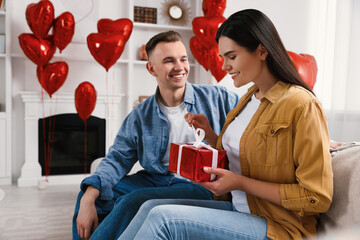 Woman opening gift from her boyfriend indoors. Valentine's day celebration