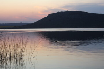 Atardecer en una hermosa laguna, junto a sierras y plantas