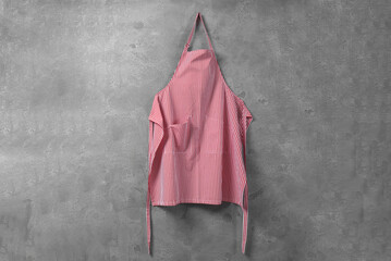 Clean red striped apron on grey tiled wall