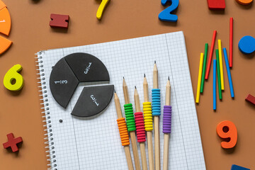 Fractions, rulers, pencils, notepad on brown background. Set of supplies for mathematics and for...