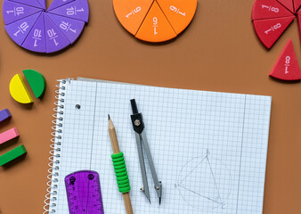 Fractions, rulers, pencils, notepad on brown background. Set of supplies for mathematics and for...