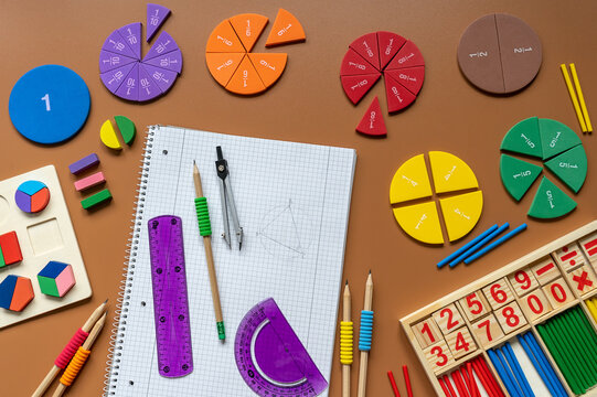 Fractions, rulers, pencils, notepad on brown background. Set of supplies for mathematics and for school. Back to school, fun education concept - Powered by Adobe