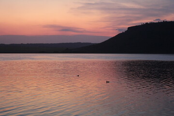 Atardecer en una hermosa laguna, junto a sierras y plantas
