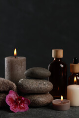 Obraz na płótnie Canvas Beautiful composition with burning candles, spa stones and different care products on dark grey table