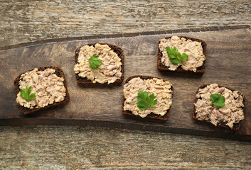 Tasty sandwiches with cod liver and parsley on wooden table, top view