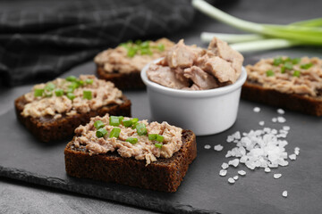 Tasty sandwiches with cod liver, salt and green onion on grey table