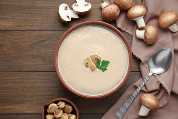 Delicious mushroom cream soup with parsley served on wooden table, flat lay. Space for text