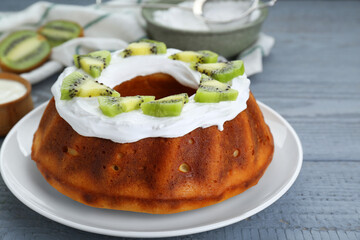 Homemade yogurt cake with kiwi and cream on grey wooden table, closeup