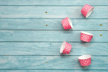 Pink polka dot cupcake cases on blue wooden floor. Material for baking.