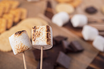 marshmallows, chocolate and cookies for making smore on brown background. view from above. copy...