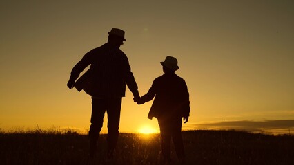 Fototapeta na wymiar Dad plays with his kid outdoors in park. Father and son walk together holding hands in park at sunset. Silhouette, happy family, baby dad travel to sunset. Childhood dream, fatherly. Child adolescence