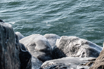 Icy cold rocks on winter blue lake.