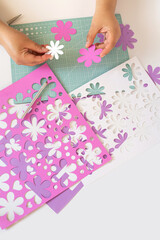 Manos con cortes de papel preparando diseño de flores, herramienta de corte utilizada en artes y...