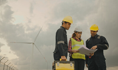 Three technician engineer in uniform with standing and checking wind turbine power farm power generator Station. Clean energy and environment.