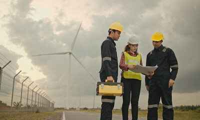 Fototapeta na wymiar Three technician engineer in uniform with standing and checking wind turbine power farm power generator Station. Clean energy and environment.