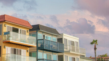 Panorama Puffy clouds at sunset Neighborhood residential buildings at La Jolla, California. There is a deck on the right with concrete tiles canopy near the buildings with sliding glass