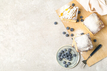 Wooden board with pieces of cottage cheese casserole and blueberry on light background