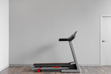 Interior of room with modern treadmill near grey wall