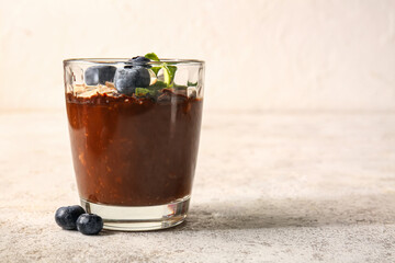 Glass of delicious chocolate pudding with blueberry and mint on white table