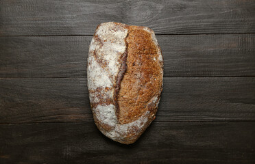 Loaf of fresh rye bread on black table