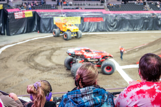 Selective focus on spectators in the stands with hearing protection watching a monster truck rally. 