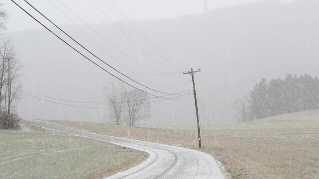Winter snowy road landscape with leaning utility pole. Photograph with a country drive in a snowstorm. Short moving image video.