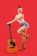 Young pin-up woman with guitar on red background