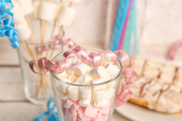 Glass of tasty marshmallows and serpentine on table, closeup