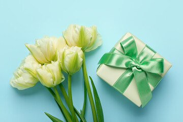 Fototapeta premium Gift box and beautiful tulip flowers on blue background. Hello spring