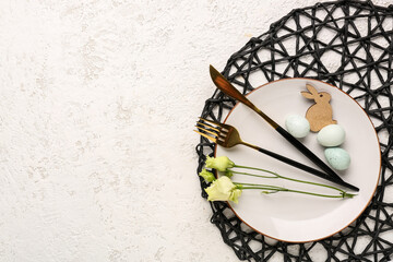 Table setting with Easter eggs, cutlery and eustoma flowers on white grunge background