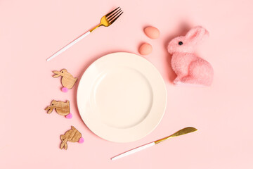 Table serving with Easter eggs and bunny on pink background