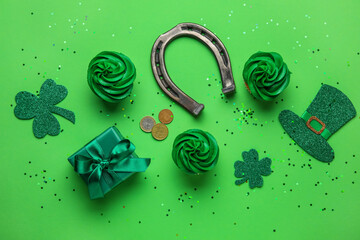 Tasty cupcakes for St. Patrick's Day, leprechaun hat, horseshoe and gift box on green background