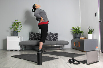 Latin adult woman with long hair and exercises in the living room of her house, stretches to start exercising at home
