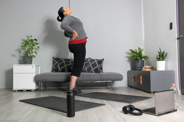 Latin adult woman with long hair and exercises in the living room of her house, stretches to start exercising at home
