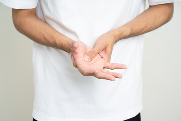 Close up man has an inflamed wrist because he is overworked. Massaged his wrists to soothe and relax. Shot on isolated white background.