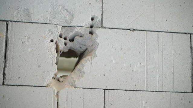 The process of making a doorway in a wall of aerated concrete bricks. A through hole in a thick gas-block wall. Holes after working perforator drill
