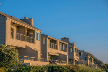 Fototapeta na wymiar Facade of homes at Del Mar Southern California on a beautiful sunny day. The two-storey beach homes with balconies overlooks the scenic sea landscape and peaceful ocean.