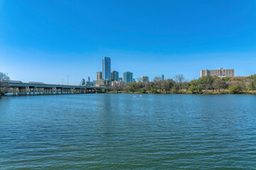 Downtown skyline in Austin Texas with Colorado River and luxury apartments. Scenic panorama of the city with bridge over water and residential buildings against blue sky.